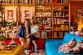 Men sitting in maximalist living room space with items on bookshelves