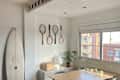 sunny all-white dining room with a surf board and rackets on the wall