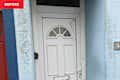 White front door with arched window, blue wall, and house number 8.