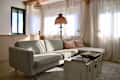 Cozy living room with a light green sectional sofa, decorative pillows, a vintage lamp, and a wooden coffee table.