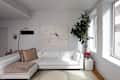 Bright living room featuring a white sectional sofa with decorative pillows, a black floor lamp, a large abstract painting, and a potted plant.