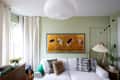 Crane artwork above white sofa in green painted living room.
