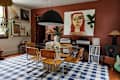Dining area featuring a glass table with wooden chairs, a large artwork, and vintage audio equipment.