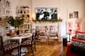 Cozy living space with a round dining table, bookshelves, a fireplace adorned with greenery, and a vintage photo above.