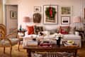 Cozy living room with a white sofa, colorful pillows, a dog resting, and a wooden coffee table with books and flowers.