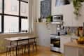 Modern kitchen with a wooden dining table, black and white decor, plants, and a bowl of bananas.