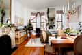 Cozy living space decorated for the holidays, featuring a small Christmas tree, dining table with floral centerpiece, and a fireplace.