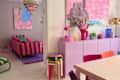 Colorful living space featuring a striped pink sofa, a pink cabinet with decorative items, and a dining table with vibrant chairs.