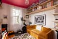 Gold velvet sofa in home office with organized shelves above.