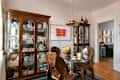 Brass pendant above table in dining room with two curio cabinets.