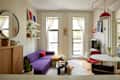 Cozy living room with a purple sofa, round coffee table, and a dog on a rug, featuring plants and bright decor.