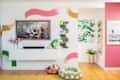 Colorful living room with a floral painting, green shelf, decorative items, and pet beds on wooden flooring.