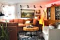 Cozy living room with a rust-colored sectional sofa, wooden coffee table, and various framed artworks on the walls.