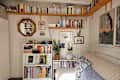 Cozy living space with a white sofa, bookshelves filled with books, framed art, a mirror, and a potted plant.