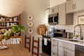 Modern kitchen with gray cabinets, black appliances, a blue coffee maker, and decorative plates on the wall.
