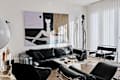 Modern living room featuring a black leather sofa, abstract wall art, and a marble coffee table with decor items.