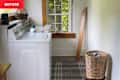 Laundry room with a white washing machine, green detergent, a wicker basket, and a window with natural light.