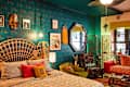Vibrant bedroom featuring a peacock headboard, colorful pillows, patterned wallpaper, and eclectic decor elements.