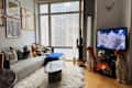 Cozy living room with a gray sofa, colorful cushions, a cactus, and two leopard statues beside a TV.