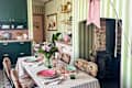 Bright kitchen with green cabinets, striped walls, leopard print chairs, a floral centerpiece, and a wood stove.