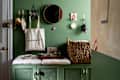 Entryway with green walls, a round mirror, a woven basket, and decorative items on a green cabinet.