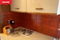 Kitchen corner with red tiled backsplash, beige cabinets, an orange device, and papers on the counter.