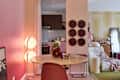 Modern dining area featuring a round table, pink chairs, decorative plates on the wall, and a cozy armchair.