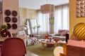 Living room with a green rug, modern furniture, large windows, and decorative items like plates and a lamp.