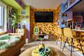 Colorful living space featuring leopard print walls, a brown leather sofa, and yellow bar stools. A small dog rests on a green blanket.