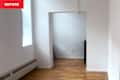 Empty room with hardwood flooring, white walls, and a small black dresser in the corner. Natural light from a window.