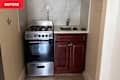 Compact kitchen area featuring a stainless steel gas stove, a small sink, and dark wood cabinetry.