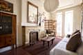 Cozy living room featuring a light sofa, wooden coffee table, and a decorative fireplace with a mirror above it.