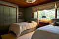Cozy bedroom with two twin beds, wooden ceiling, green walls, and a window with natural light.