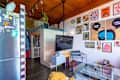 Cozy living space with a TV, colorful artwork on walls, a dog resting, and a mix of modern furniture.