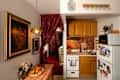 Cozy kitchen with wooden cabinets, a gas stove, and a decorative curtain. A table holds a basket of oranges and flowers.
