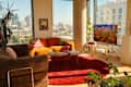 Cozy living room with orange curved sofa, red rug, wooden coffee table, and a TV displaying colorful jellyfish.