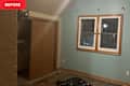 Room with light blue walls, wooden trim, a closet door, and a window with grid panes; black trash bag on the floor.