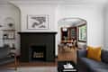 Living room with a dark brick fireplace, modern furniture, and a dining area featuring a wooden table and white chairs.