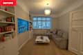 Living room with a light gray sectional sofa, white coffee table, colorful bookshelf, and a large blue artwork.