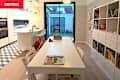 Bright kitchen and dining area with a white table, bookshelves, and sliding glass doors leading to a garden.