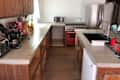 Kitchen with wooden cabinets, concrete countertops, red stove, stainless steel fridge, and various appliances on the counter.