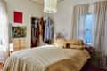 Cozy bedroom with a large bed topped with yellow bedding, a teddy bear, and a colorful painting on the wall.
