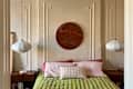 Cozy bedroom featuring a green bedspread, pink pillows, a decorative wall art piece, and pendant lights.