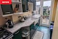 Compact kitchen with dark cabinets, granite countertops, sink, kettle, and a view of the garden through glass doors.