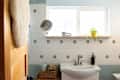 Bright bathroom with hexagonal tile, a sink, a mirror, and a potted plant on a wooden shelf.