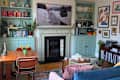 Cozy living room with a wooden dining table, colorful cushions, a fireplace, and bookshelves filled with books and decor.