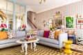 Colorful living room with a striped sofa, vibrant pillows, a white coffee table, and patterned wallpaper.