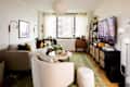 Cozy living room featuring a light gray sectional sofa, round coffee table, and a large TV on a black media console.