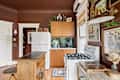 Cozy kitchen with brown walls, wooden cabinets, green tile backsplash, and vintage decor, featuring a gas stove and island.