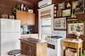 Cozy kitchen with brown walls, wooden cabinets, a white fridge, gas stove, and vintage decor on the walls.
